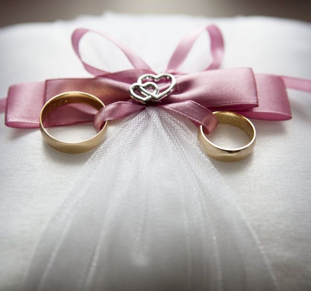 selective focus photography of silver colored engagement ring set with pink bow accent on throw pillow