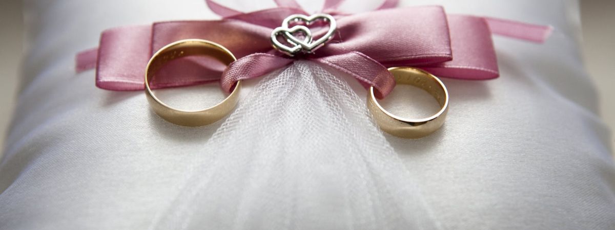 selective focus photography of silver colored engagement ring set with pink bow accent on throw pillow