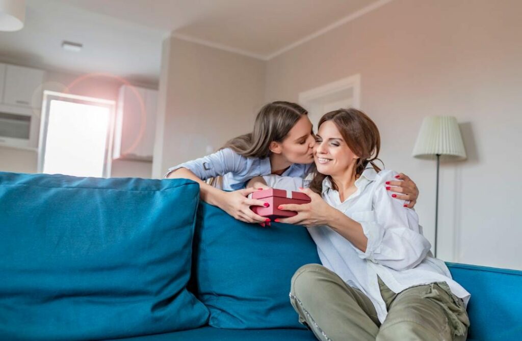 kissing mother while giving a gift hamper